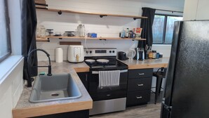 A compact kitchen with a sink, stove, and storage cabinets.