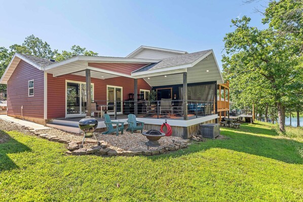 A modern house with a covered patio, outdoor seating, and a fire pit. - Lighthouse Lodge Resort - The Red House - Amazing Patio & Lake Views - Outdoor Pool! (Kimberling City)