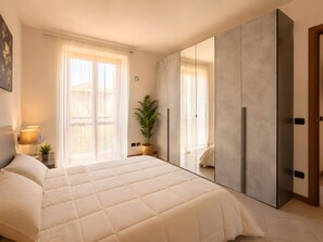 Ein Schlafzimmer mit einem Bett, einem Spiegel, einer Zimmerpflanze und einem Kleiderschrank.