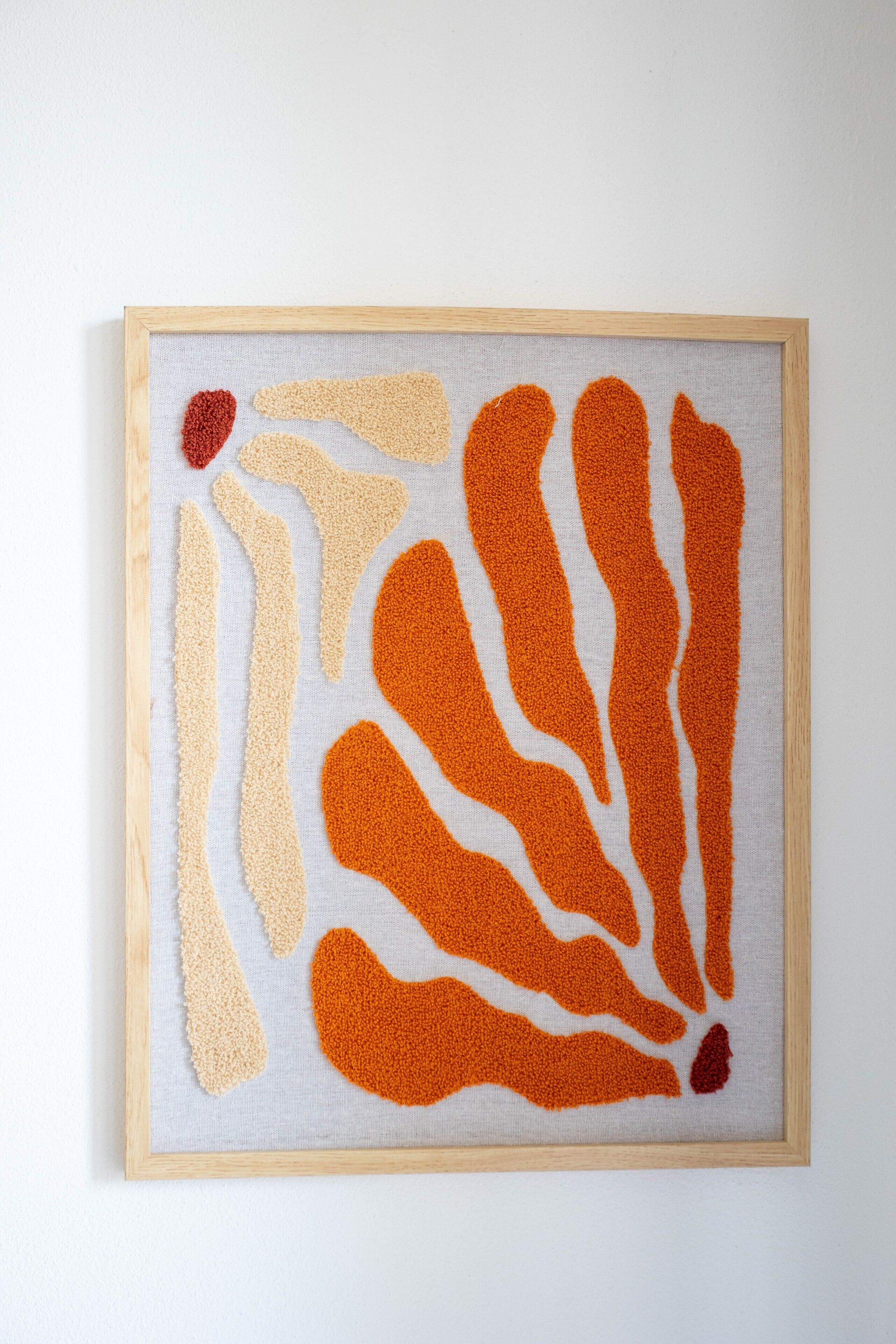 Ein gerahmtes Kunstwerk mit abstrakten Mustern in Beige und Orange.