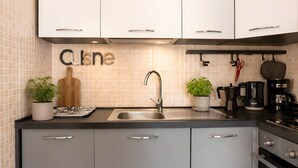 A modern kitchen with white cabinets, a stainless steel sink, and a coffee maker.