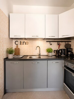 A modern kitchen with white cabinets, a stainless steel sink, and a coffee maker.
