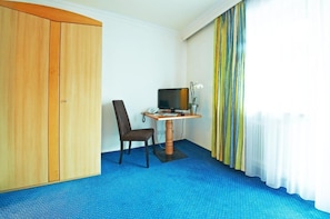 Una habitación con escritorio, silla, televisor y armario.