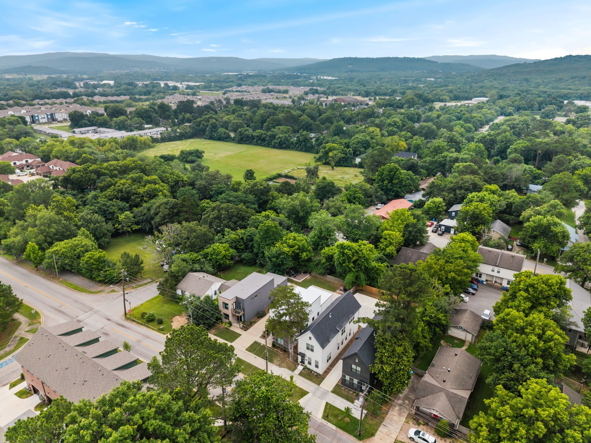 An aerial view of a residential area with houses, roads, and green spaces.