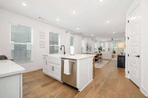 A spacious kitchen with a central island, white cabinetry, and a dishwasher. - Moxie - 1.5 Miles From DT & UofA (Fayetteville)