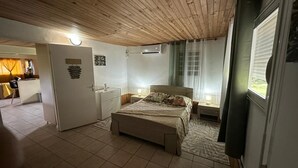 Et soveværelse med seng, sengeborde, et klædeskab, en dør og et vindue.