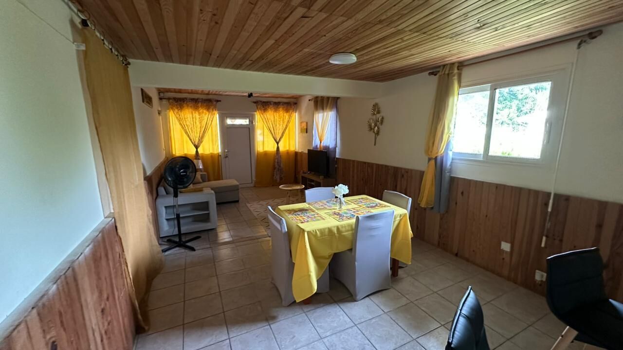 A dining area with a table set for four, a television, and a fan.