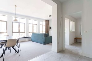 Uma sala de estar ampla com uma mesa de jantar, cadeiras, um sofá e um banco.