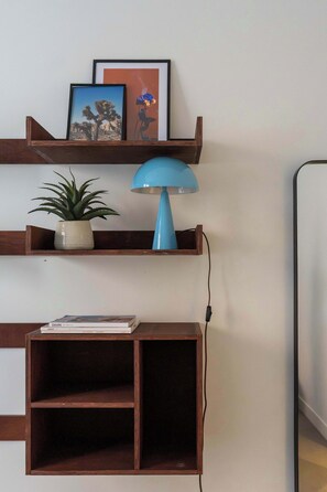 Eine Wandablage mit einem Topfpflanzen, einer blauen Lampe und gerahmten Bildern.