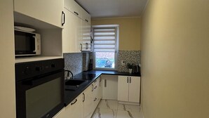 Cocina con microondas, horno y encimera negra.