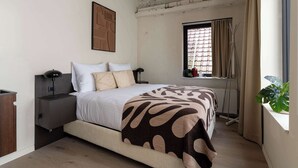 A bedroom with a bed, bedside tables, a radiator, a window with curtains, and a plant. - Elegant City Room near Antwerp Cathedral (Antwerpen)
