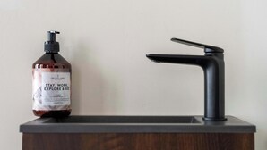 A bathroom with a dark wooden vanity, a black faucet, and a bottle of hand sanitizer. - Elegant City Room near Antwerp Cathedral (Antwerpen)