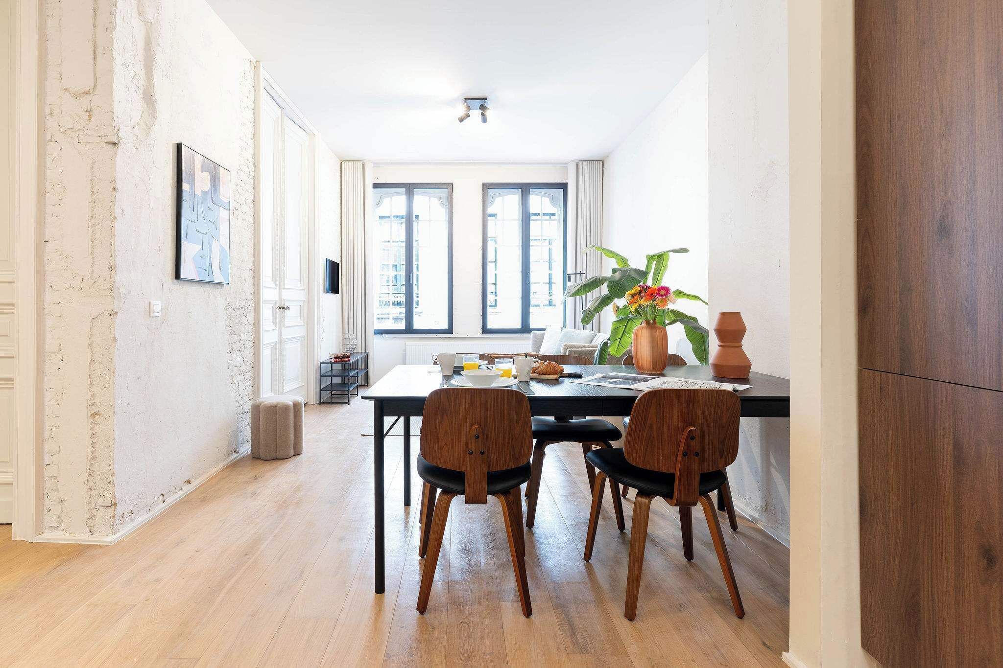 Un comedor con mesa, sillas y una planta.