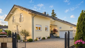 A two-story house with a paved driveway, a gated entrance, and a garage. - Villa Luna – Stylish Living. Arrive feeling relaxed. Feel at home. (Schaafheim)