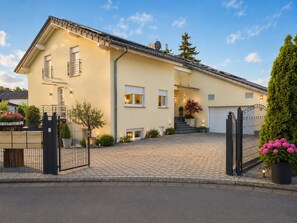 Uma casa de dois andares com um caminho de entrada pavimentado, um portão e uma garagem.