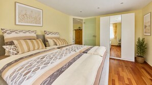 A bedroom with a bed, a potted plant, and a door leading to another room. - Villa Luna – Stylish Living. Arrive feeling relaxed. Feel at home. (Schaafheim)