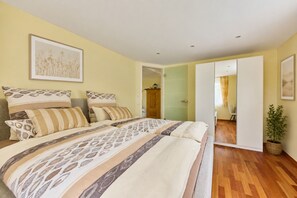 Quarto com cama, planta em vaso e porta para outro cômodo.