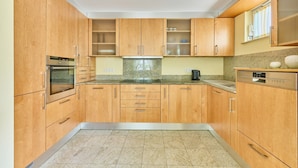 A kitchen with wooden cabinets, a built-in oven, a microwave, a coffee maker, and a dishwasher. - Villa Luna – Stylish Living. Arrive feeling relaxed. Feel at home. (Schaafheim)