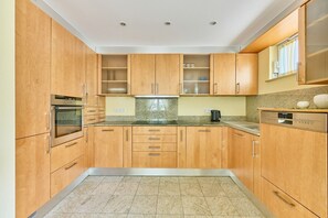 Uma cozinha com armários de madeira, forno embutido, micro-ondas, máquina de café e lava-louças.