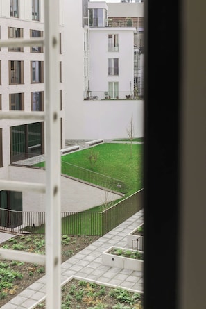 A residential building with multiple balconies, a central courtyard with a lawn, and a gated entrance. - ROMY | Bright Modern Room for 2 in Antwerp (Antwerpen)