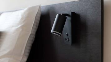 A modern bed with a black headboard, a white pillow, and a bedside control panel.
