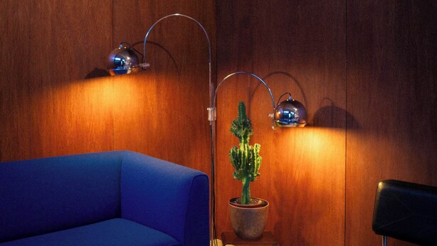 A room with a blue sofa, a black chair, a cactus plant, and two wall-mounted lamps. - ROMY | Charming Attic Double Room (Antwerpen)