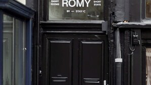 A black double door with a sign above it that reads 'SMART ROMY SHORT STAYS BY STAY-C.' - ROMY | Charming Attic Double Room (Antwerpen)