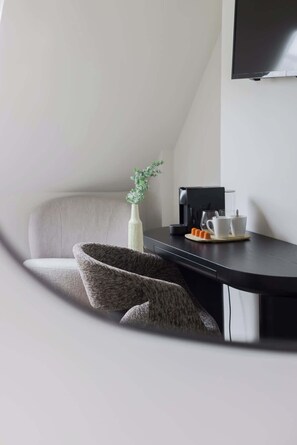 Una habitación moderna con sofá, una mesita de centro, una planta pequeña y una cafetera.