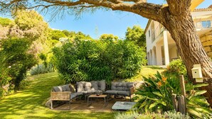 A patio with outdoor furniture, a large tree, and a building in the background. - Luxury Villa for 12 Guests with Heated Pool in St. Maxime, La Nartelle Private Estate (Sainte-Maxime)