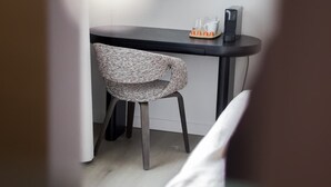 Ein kleiner, moderner Raum mit einem runden Tisch, einem Stuhl, einem Spiegel und einer Kaffeemaschine.