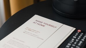 A remote control, a black kettle, and a 'Make Yourself at Home' sign on a table. - Riga Suites | Deluxe Double Room with Bath (Antwerpen)