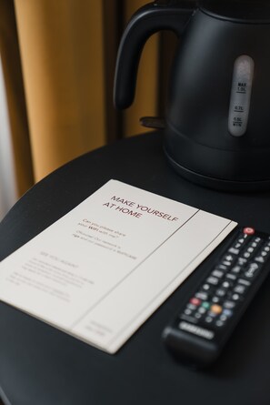 Un control remoto, una tetera negra y un cartel que dice 'Como en Casa' sobre una mesa.