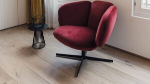 A room with a red chair, a TV on the wall, and a window with a view of buildings. - Riga Suites | Deluxe Double Room with Bath (Antwerpen)