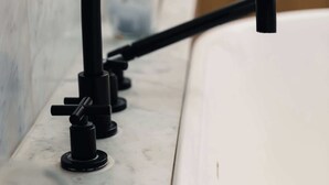 A bathroom with a white bathtub, a black faucet, and a marble wall.