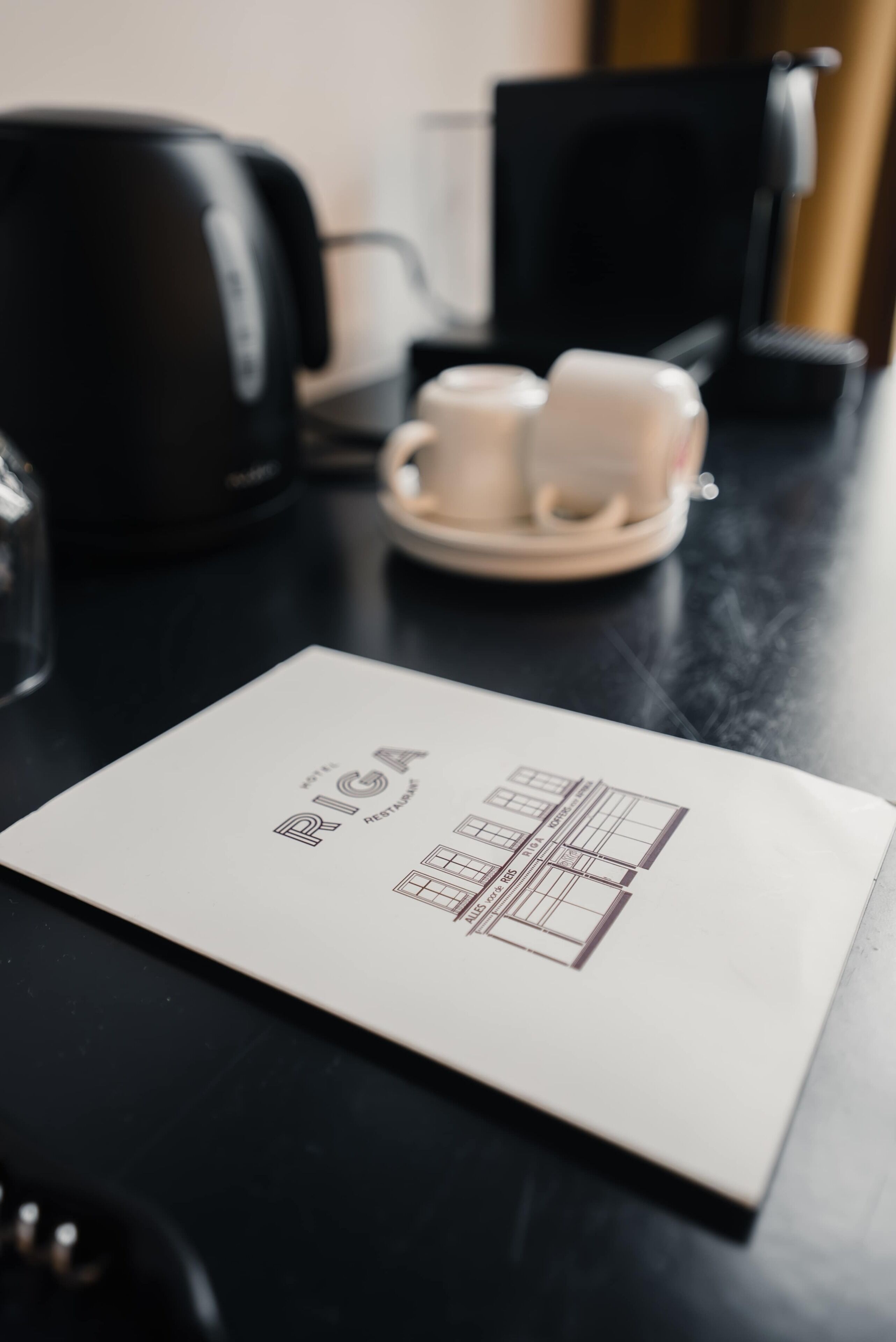 Una mesa con un menú, una cafetera y dos tazas.
