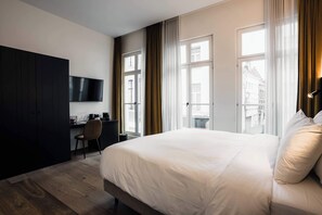 Una habitación de hotel con cama, escritorio, silla y televisor.