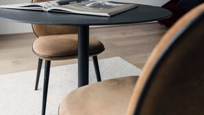 A round table with a magazine, a chair, and a red bag in a room with a white wall and wooden floor. - Riga Suites | Duplex Room with Private Terrace (Antwerpen)