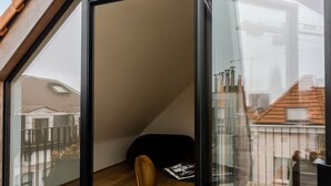 A modern room with a glass wall, a wooden ceiling, and a single chair. - Riga Suites | Duplex Room with Private Terrace (Antwerpen)