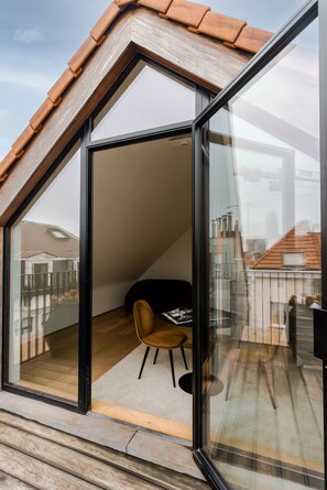 Una habitación moderna con pared de vidrio, techo de madera y una sola silla.