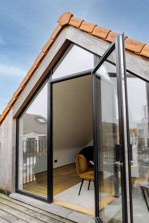 Una habitación moderna con puerta de cristal, techo de madera y una silla.