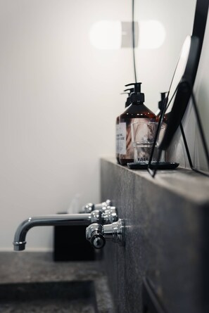Un lavabo de salle de bain avec un robinet, un flacon de savon liquide et un verre.