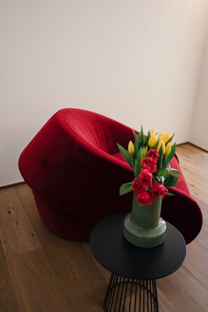 Une chaise rouge, une petite table ronde et un vase rempli de fleurs.
