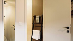 Een hotelkamer met een bed, een spiegel, een handdoekhouder en een deur naar een badkamer.
