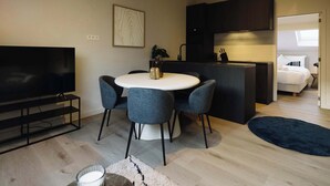 Een moderne woonruimte met een eethoek, een flatscreen televisie, een keuken en een slaapkamer.