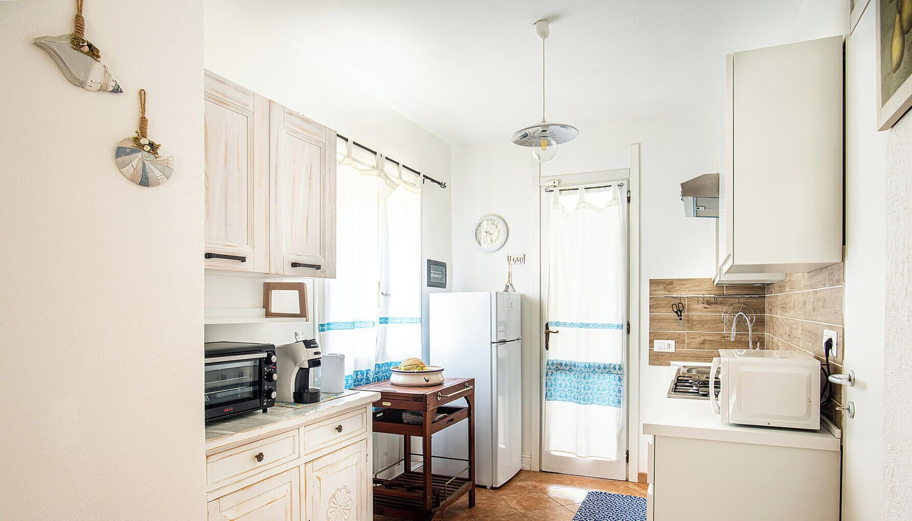 A compact kitchen with white cabinets, a coffee maker, a toaster, and a refrigerator.