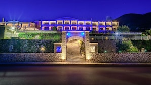 A multi-story building with a stone facade, an arched entrance, and a sign indicating it is a restaurant. - Odyssey Hotel (Kefalonia)
