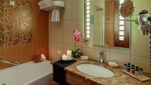 A bathroom with a bathtub, sink, mirror, and various toiletries. - Odyssey Hotel (Kefalonia)