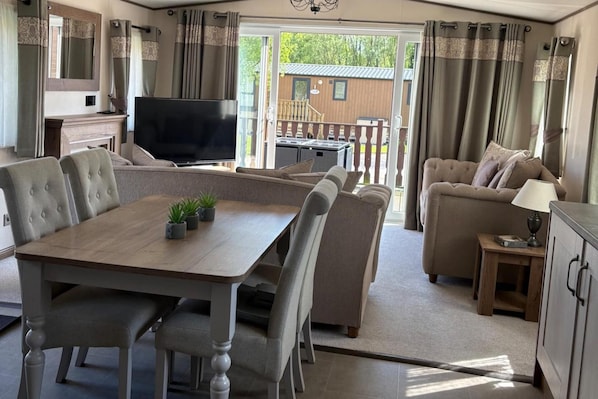 A spacious living area with a dining table, sofas, and a TV.