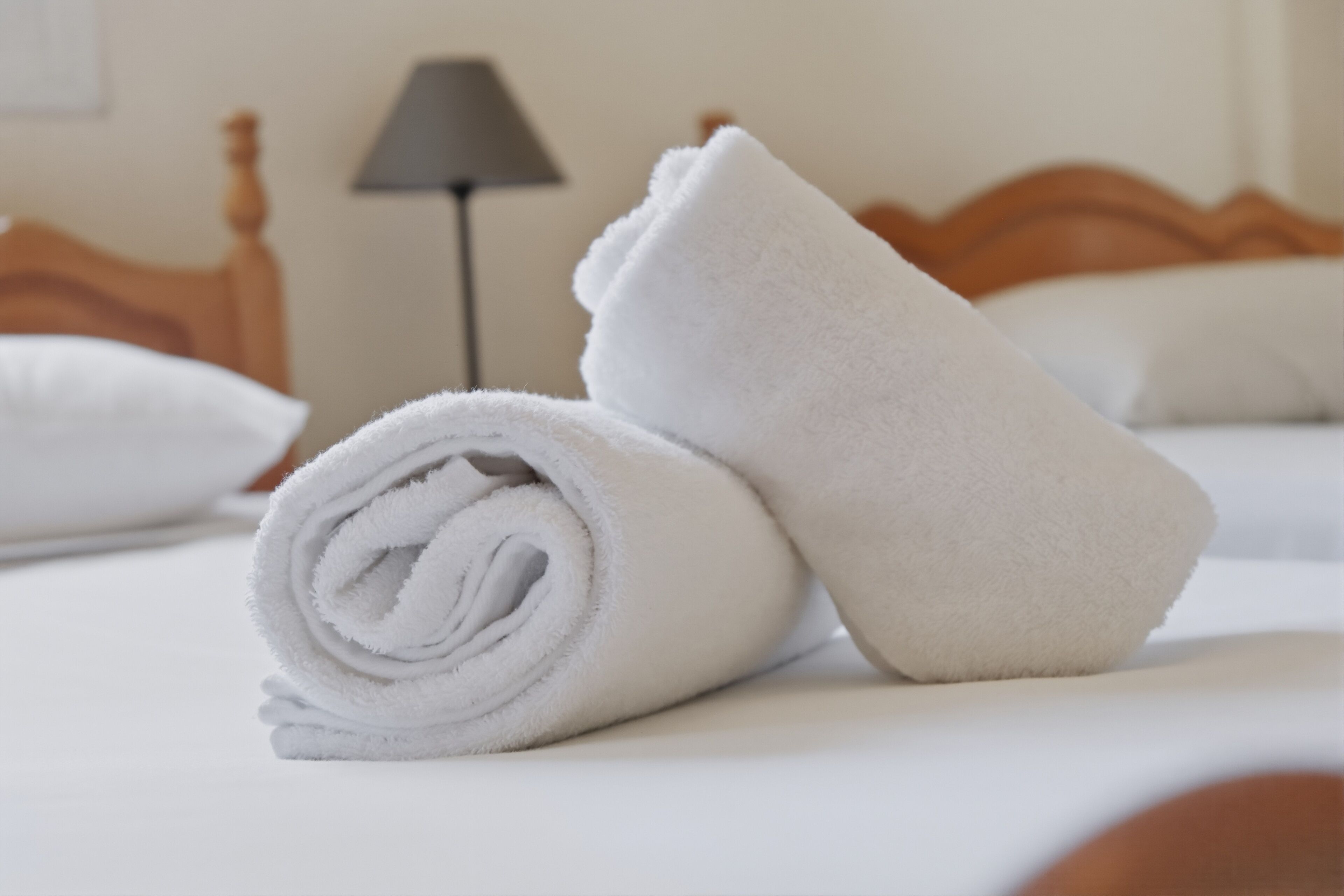 A neatly made bed with white linens and a rolled towel.