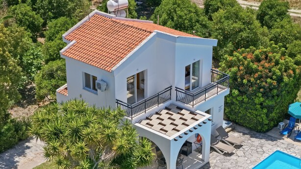 Una casa a due piani con piscina, veranda coperta e un giardino rigoglioso.